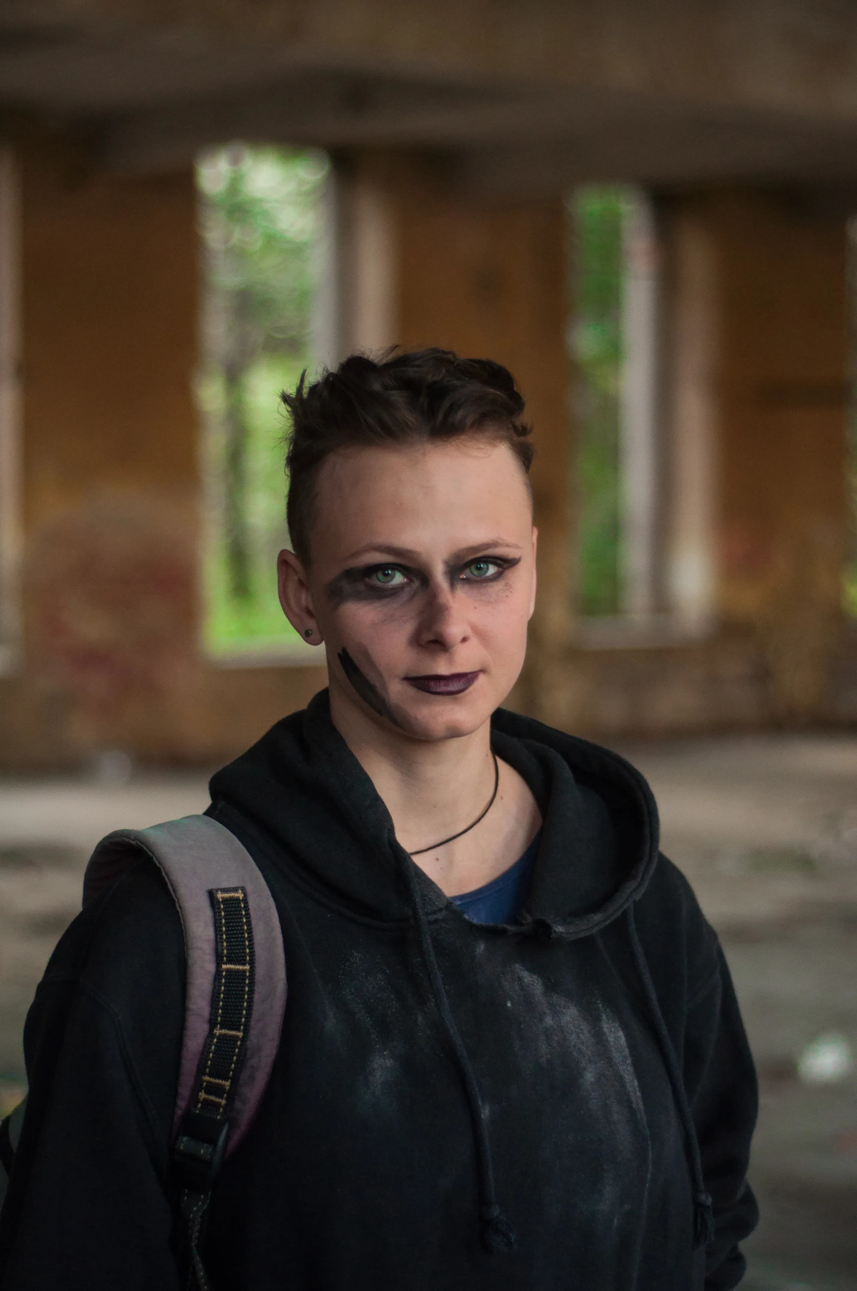 Pomalowana artystycznie tancerka stoi w ruinach budynku przemysłowego