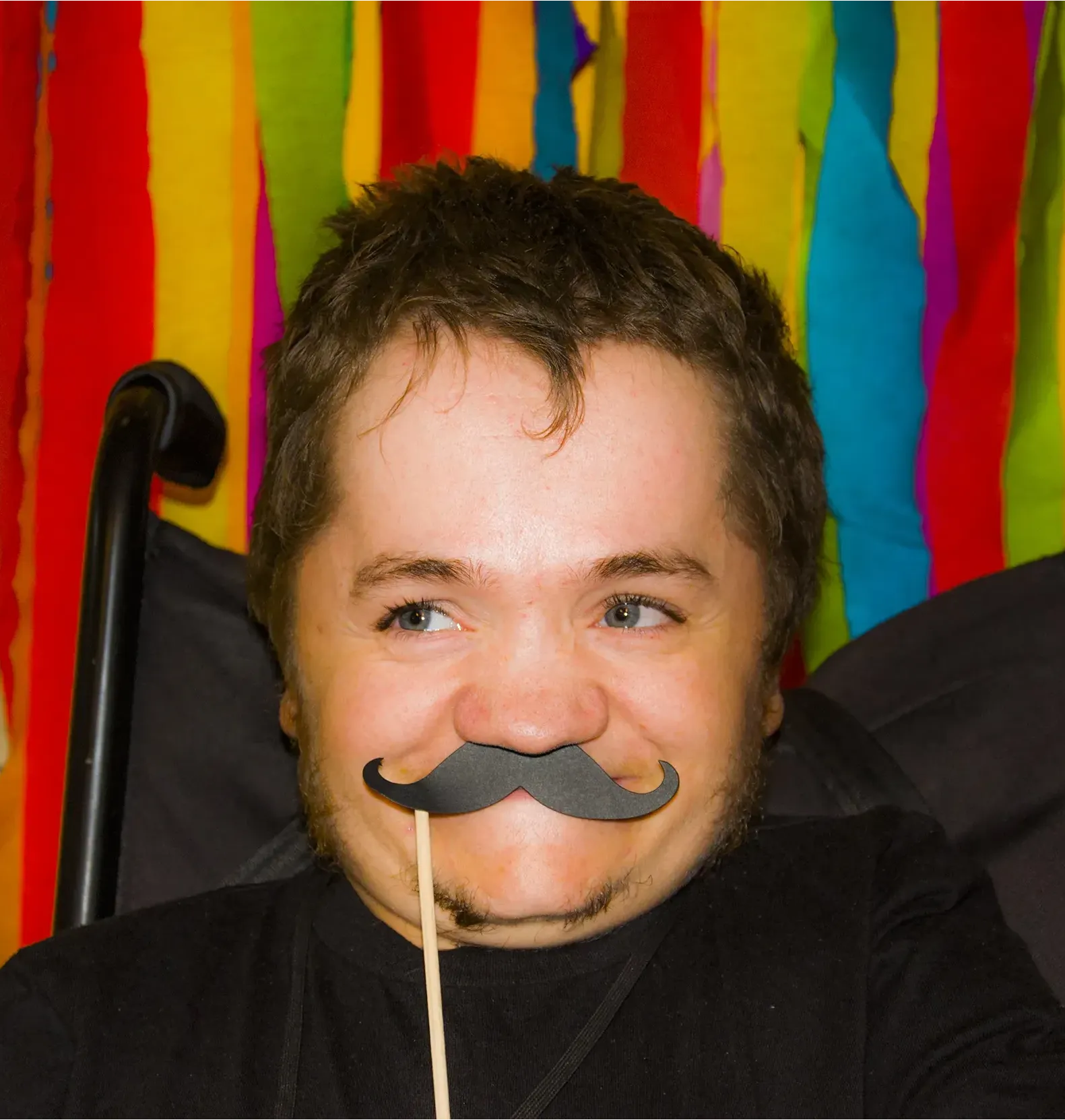 Uśmiechnięty członek grupy Niepokonanych trzyma sztuczne wąsy