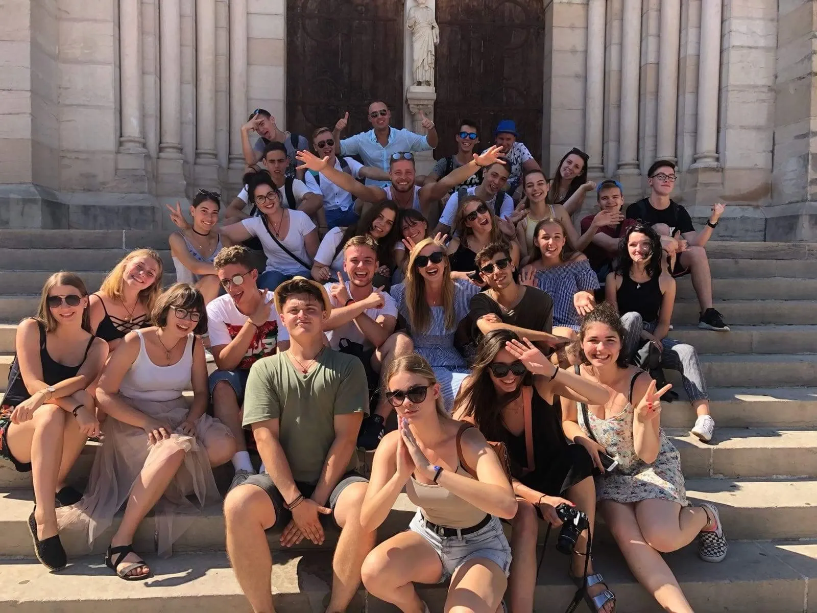 Duża grupa młodzieży siedzi na schodach przed kościołem